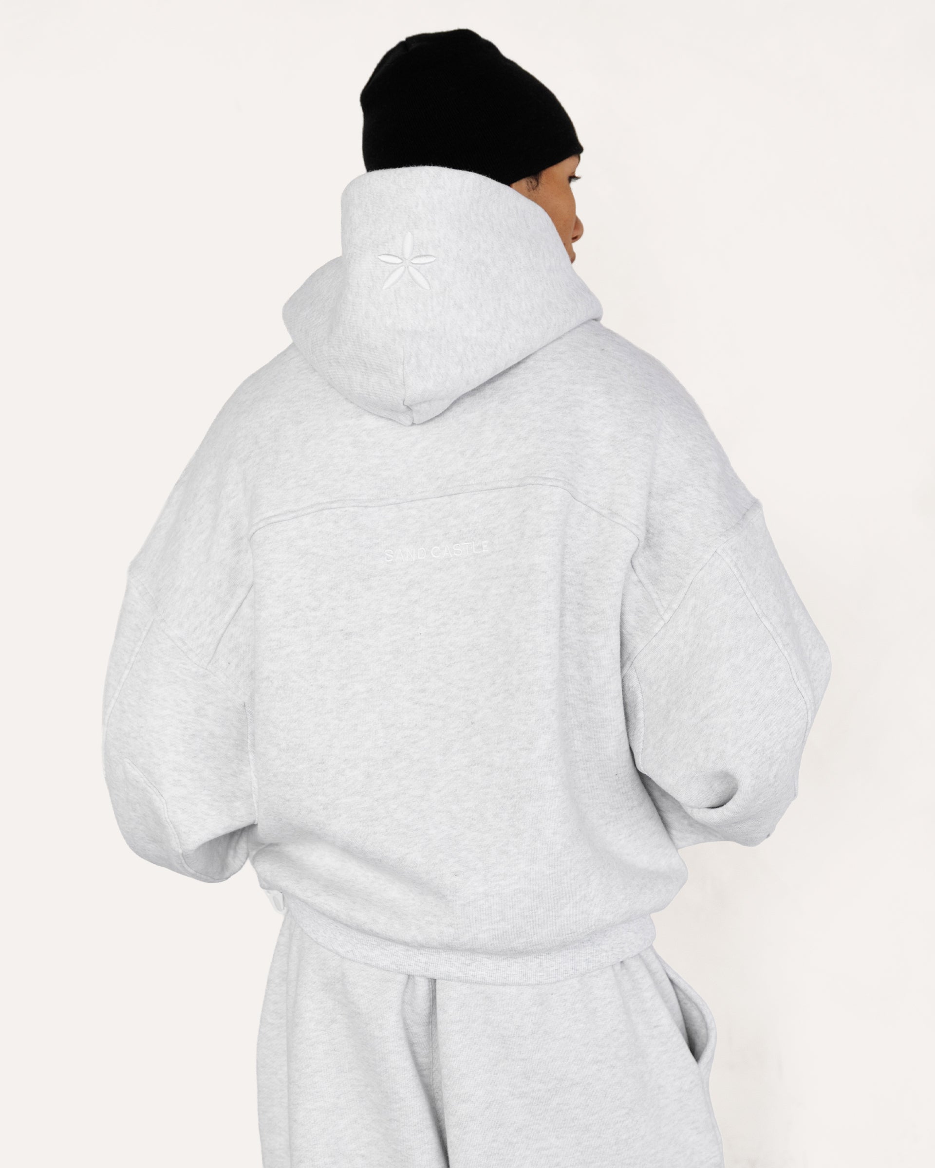 Model wearing Heritage Pullover Hoodie in heather grey, back view — Sand Castle Atelier