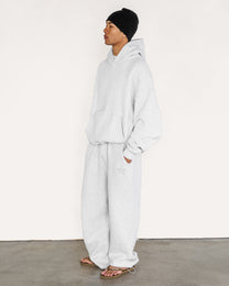 Model wearing Heritage Pullover Hoodie and matching sweatpants in heather grey, side view — Sand Castle Atelier